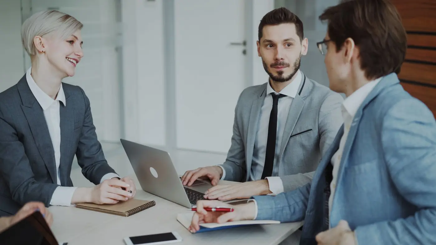 Colleagues around a table with laptops and notebooks in a bright meeting room